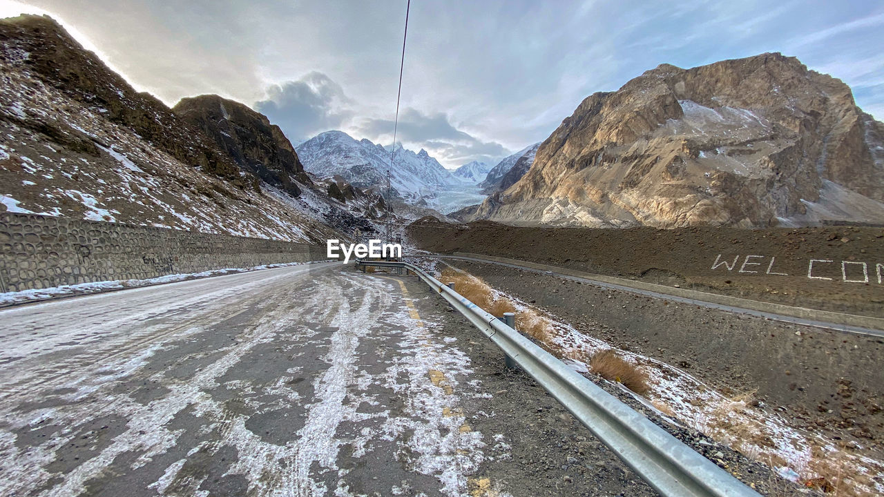 Road amidst snowcapped mountains against sky during winter