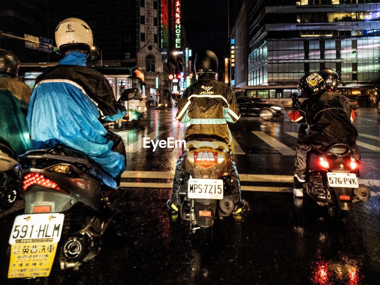 REAR VIEW OF PEOPLE WALKING ON ILLUMINATED STREET