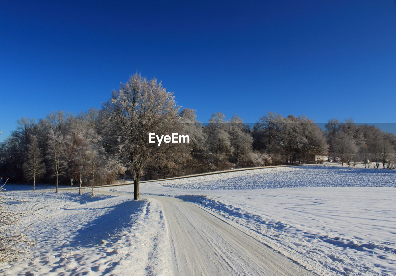 Snow covered landscape against clear blue sky