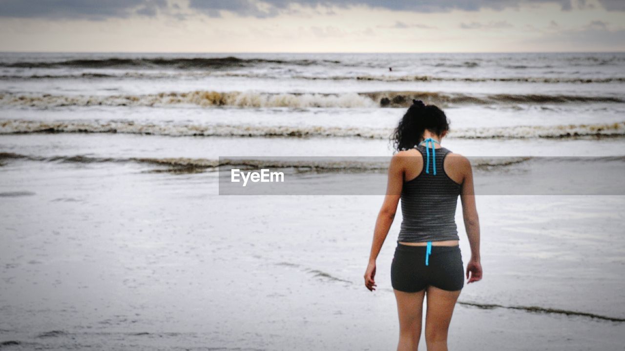 Rear view of woman walking at beach