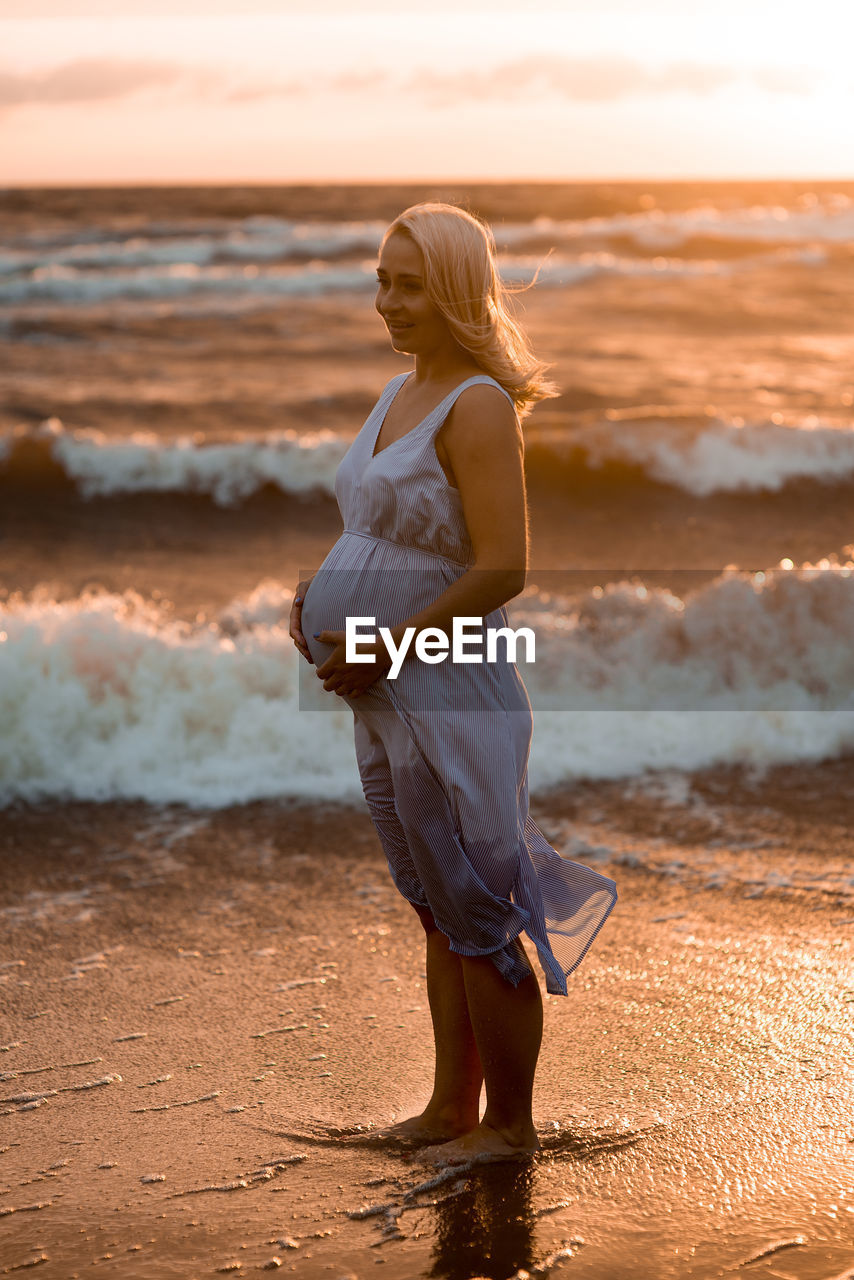 Pregnant woman standing on beach
