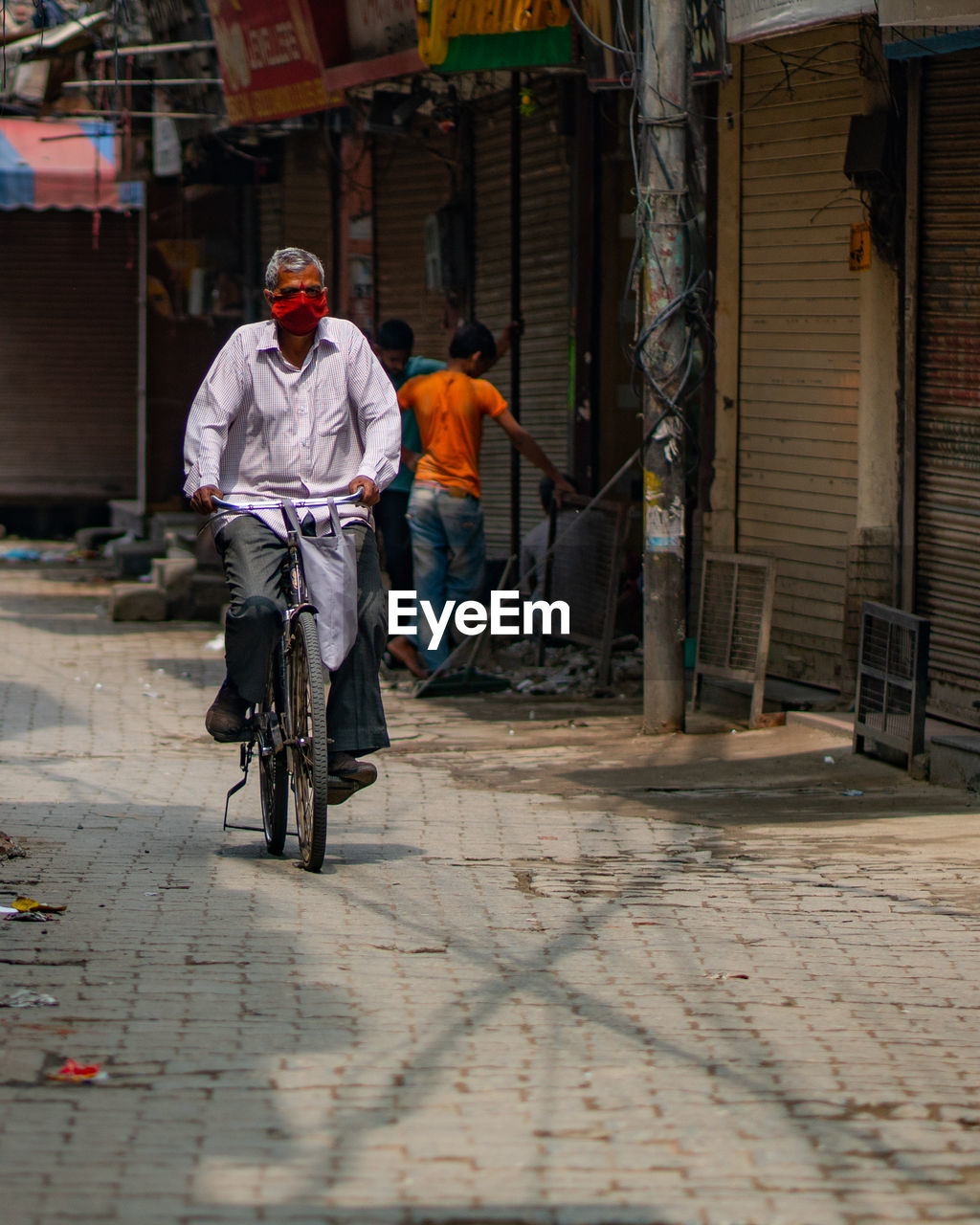 MEN RIDING BICYCLE ON STREET AGAINST BUILDINGS