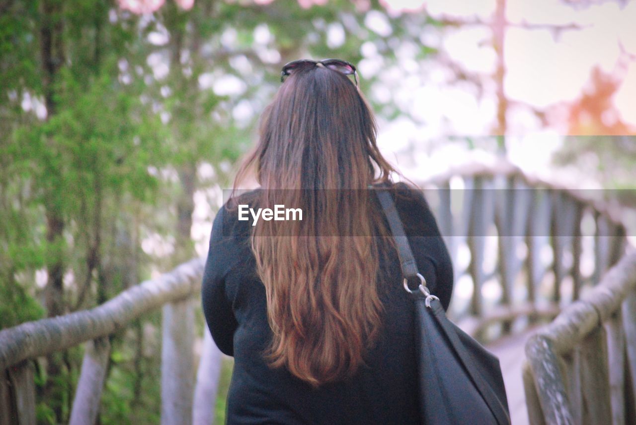 REAR VIEW OF WOMAN STANDING BY RAILING