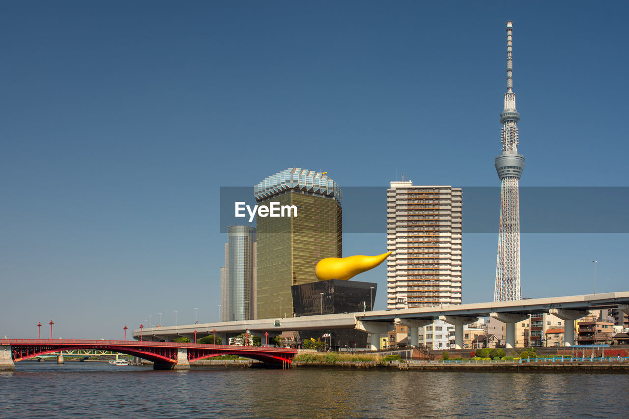 BRIDGE OVER RIVER AND BUILDINGS AGAINST SKY