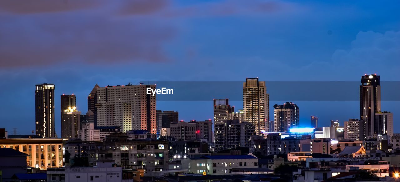 ILLUMINATED MODERN BUILDINGS AGAINST SKY AT NIGHT