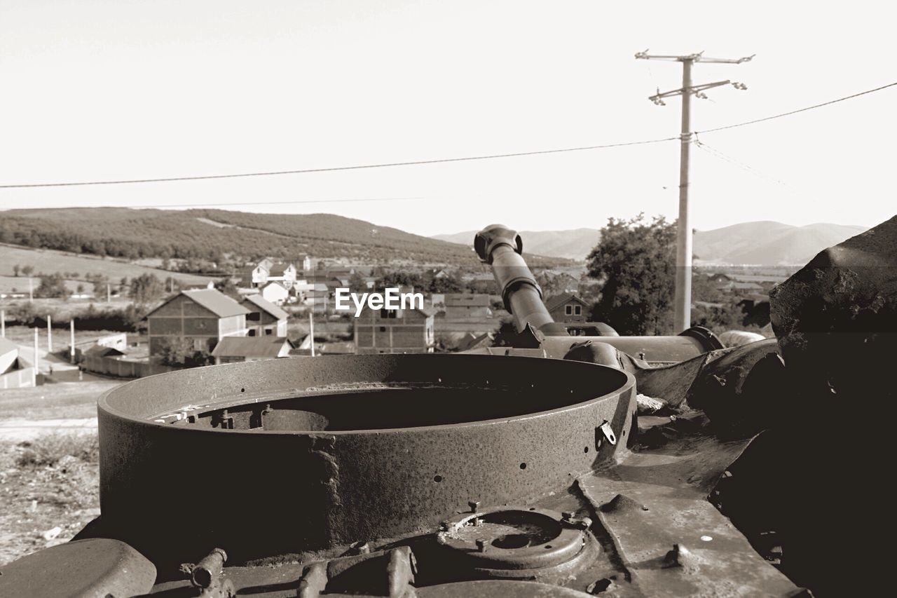 Armored tank by houses on field against clear sky