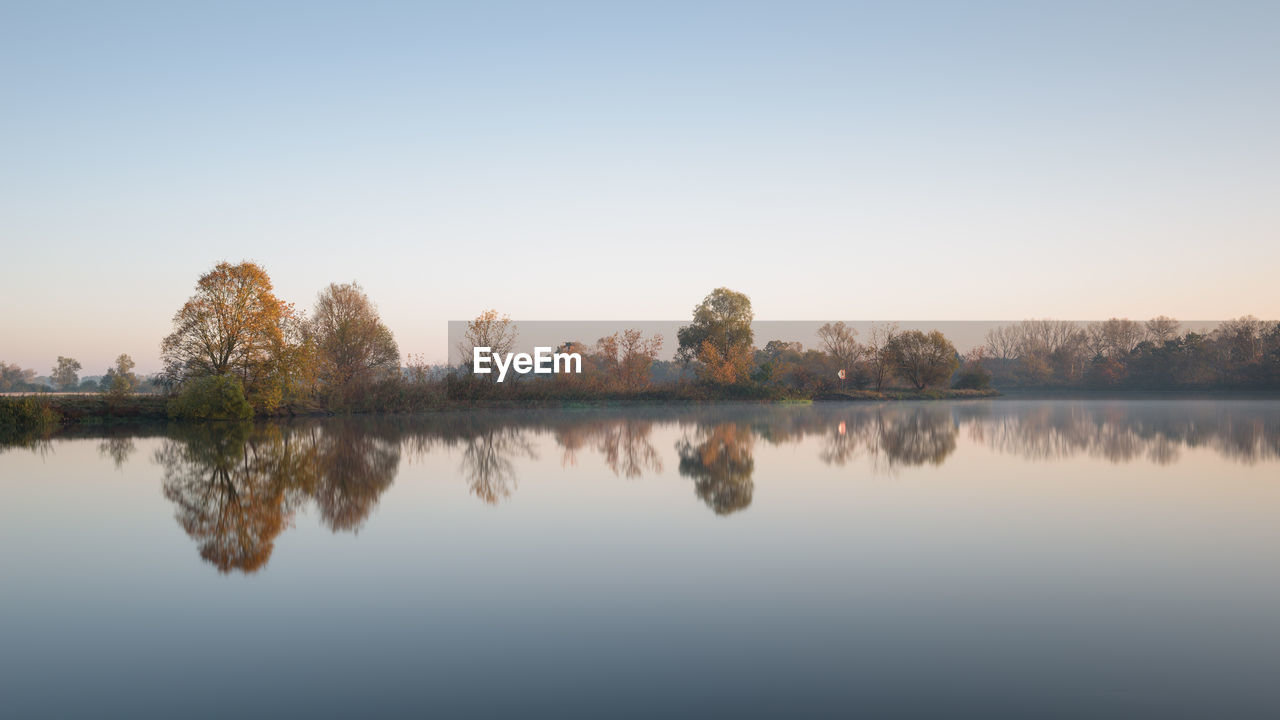 Scenic view of lake against clear sky during sunset