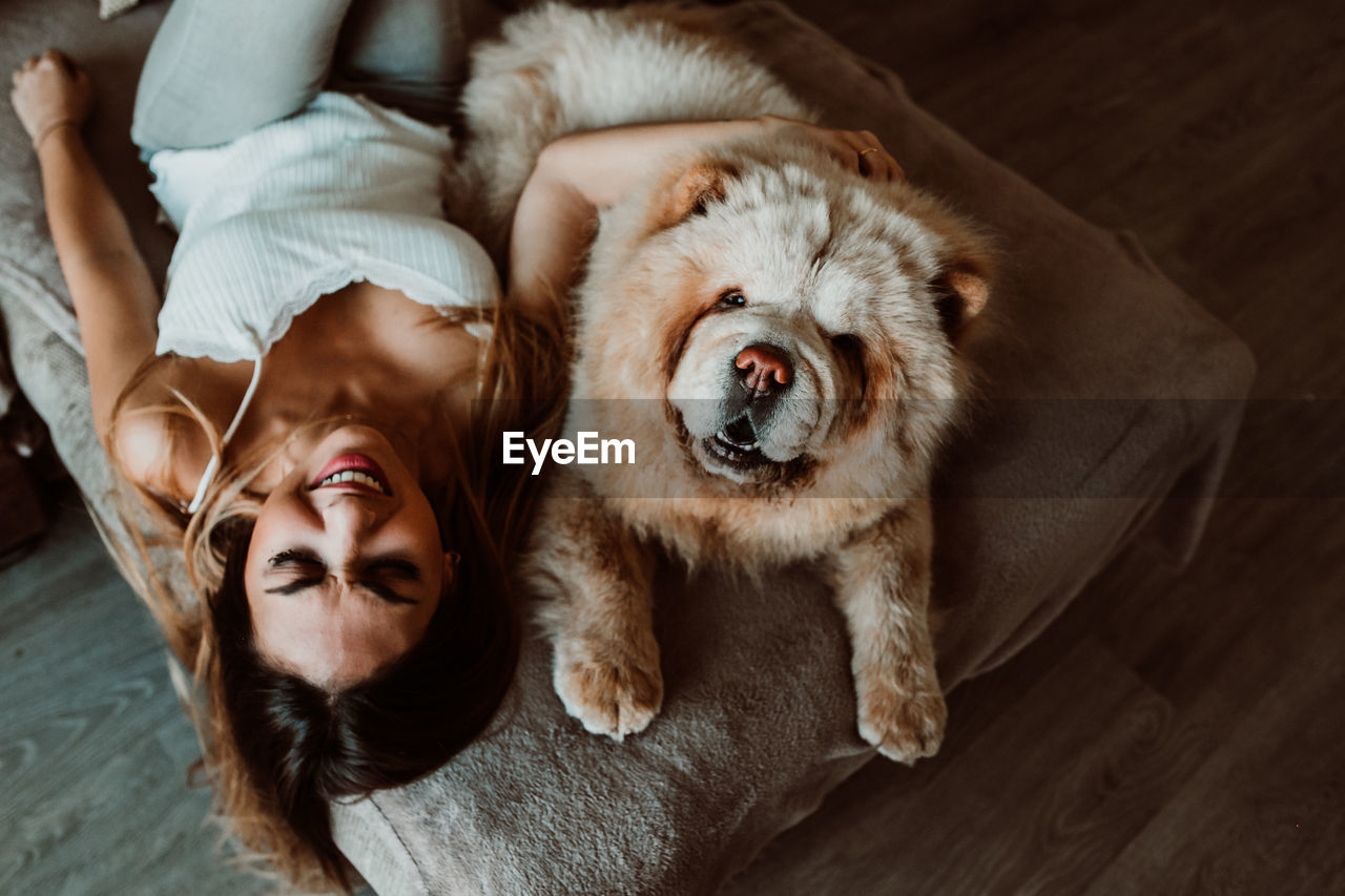 High angle view of young woman with dog lying on bed at home