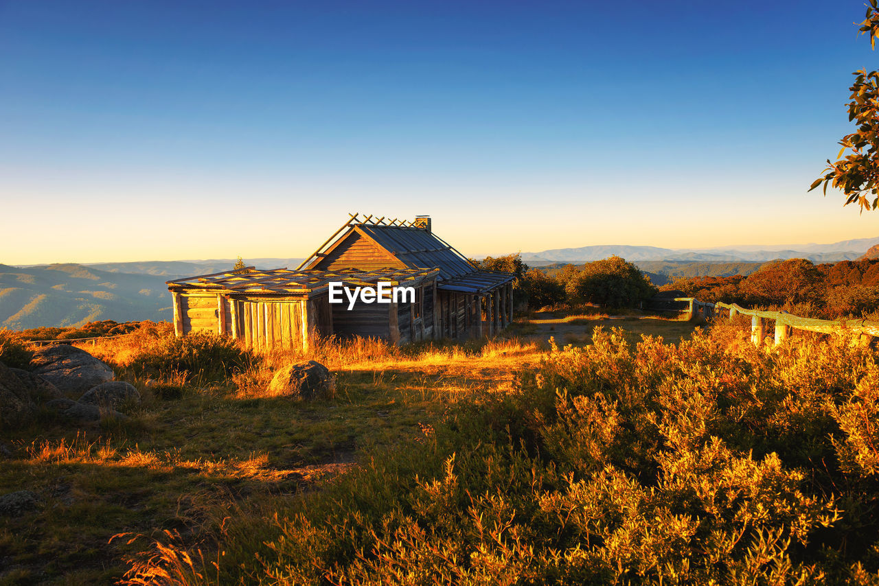 HOUSE ON FIELD BY BUILDING AGAINST SKY