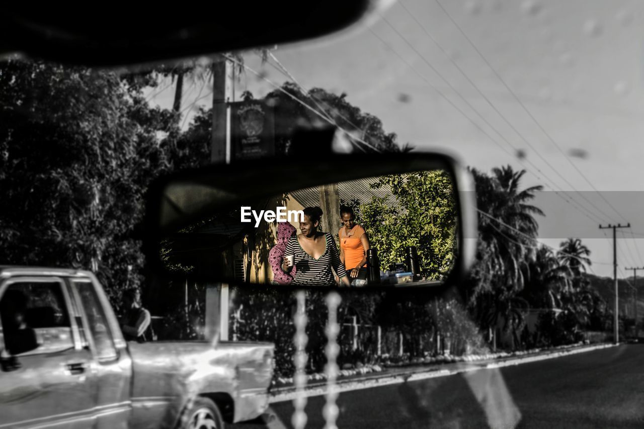 REFLECTION OF WOMAN PHOTOGRAPHING ON SIDE-VIEW MIRROR