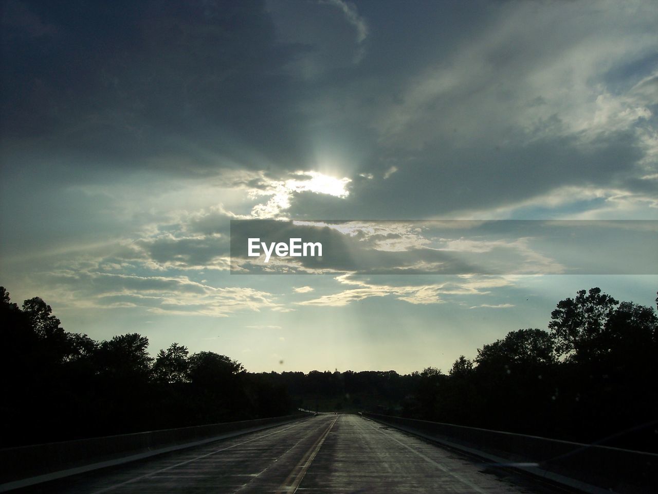 Country road against cloudy sky at sunset