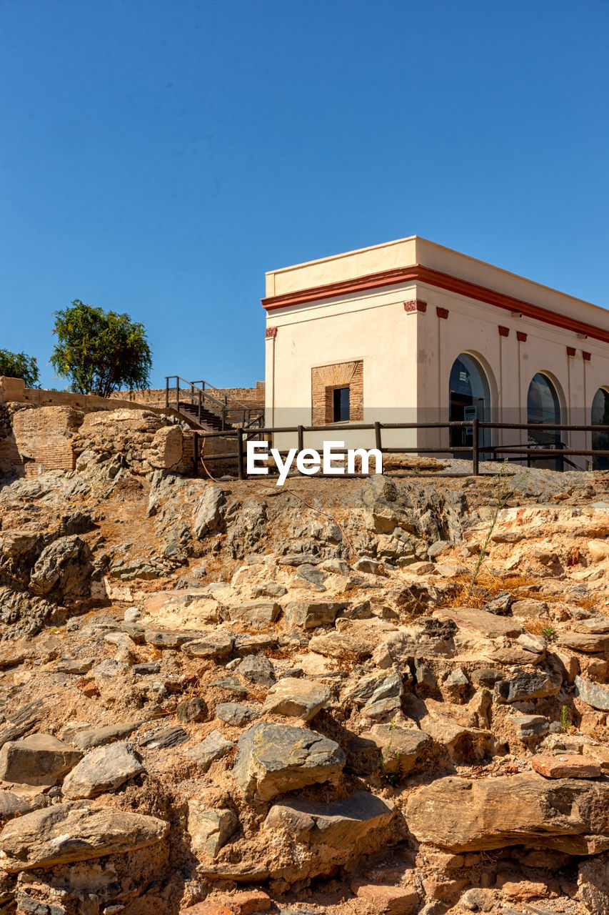 architecture, built structure, building exterior, clear sky, sky, blue, building, nature, wall, ancient history, ruins, house, no people, rock, sunny, history, day, outdoors, copy space, land, sunlight, the past, landscape