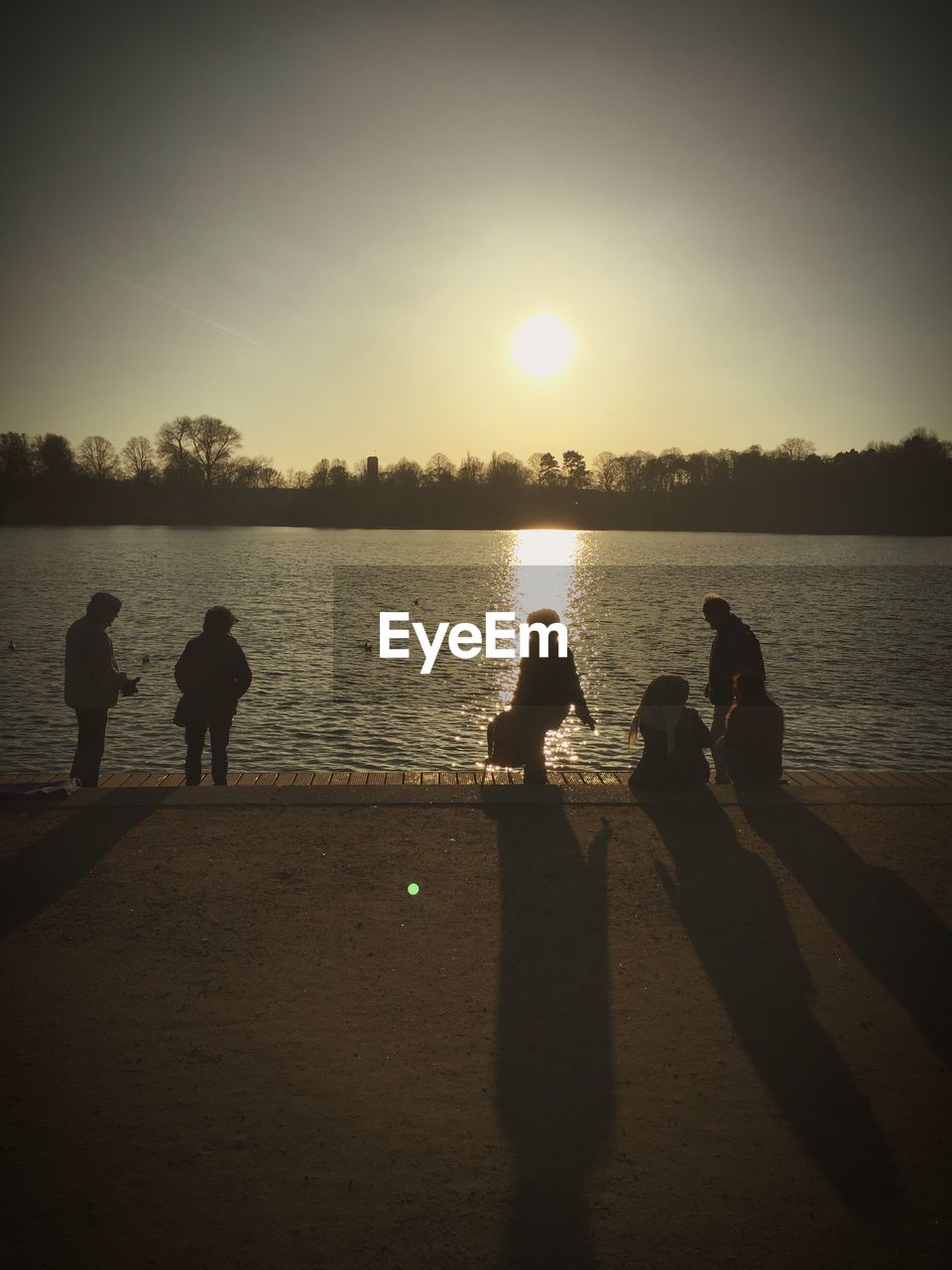 REAR VIEW OF SILHOUETTE MEN ON LAKE AGAINST SKY