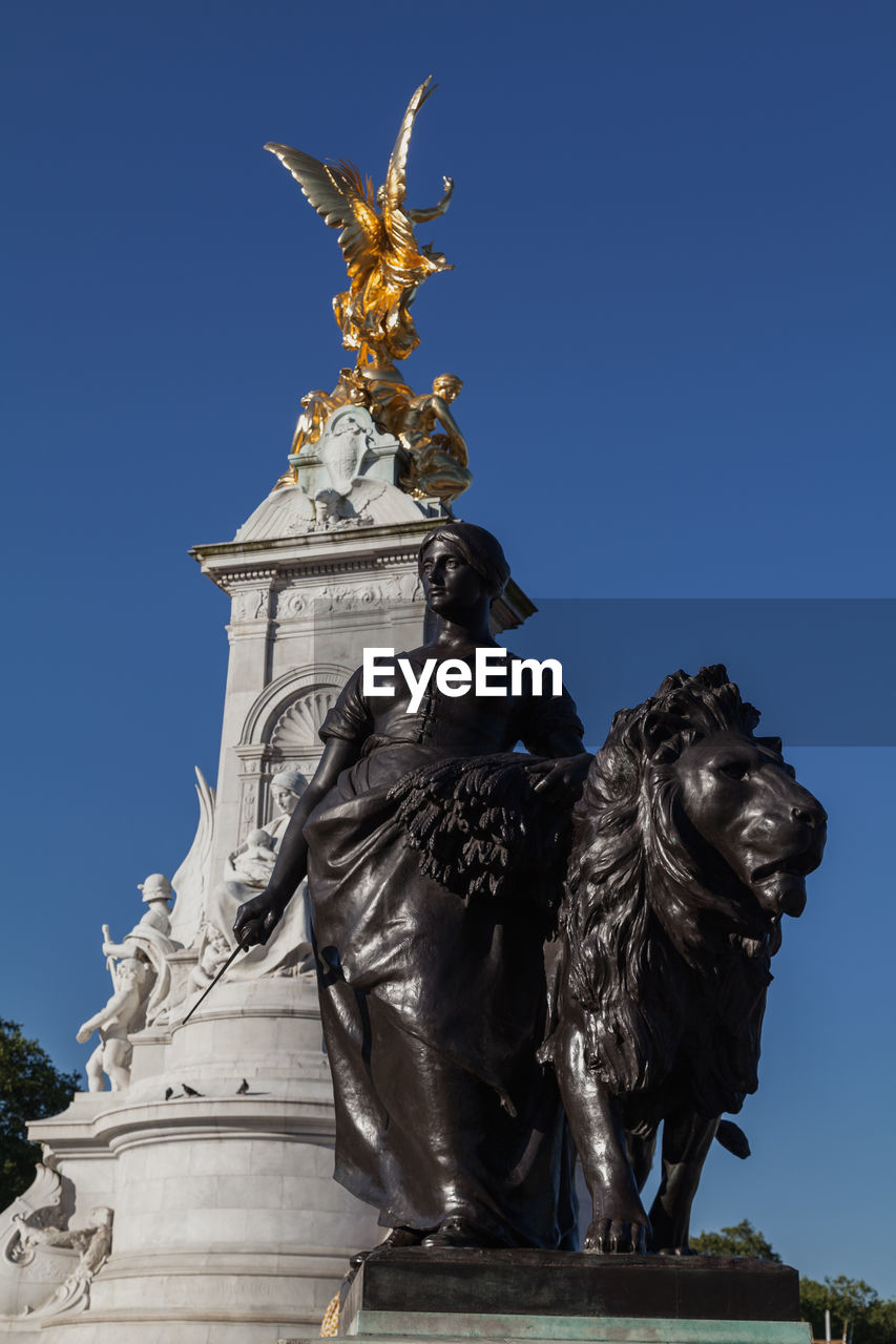 Low angle view of statues against clear blue sky at buckingham palace