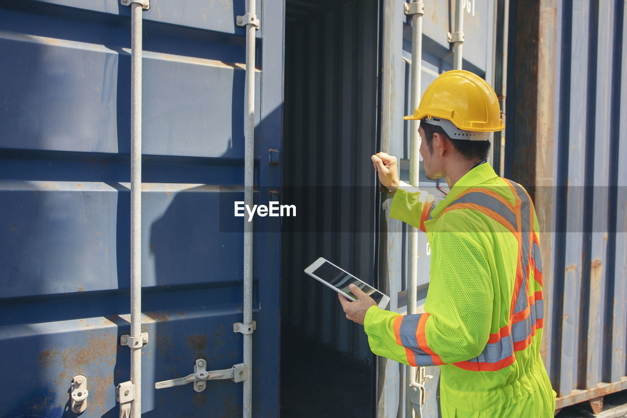 MAN WORKING WITH MOBILE PHONE WHILE STANDING ON OFFICE