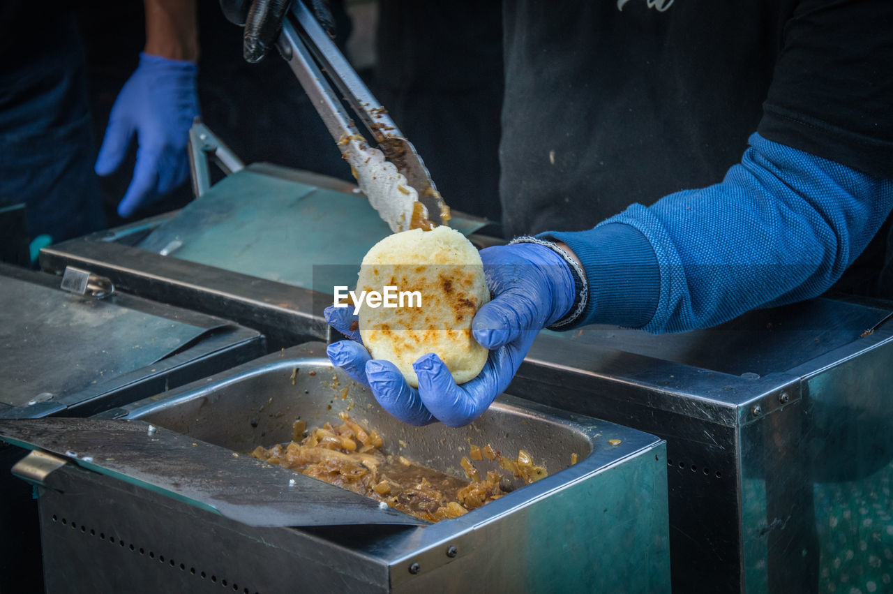 Midsection of man preparing arepa on barbecue grill