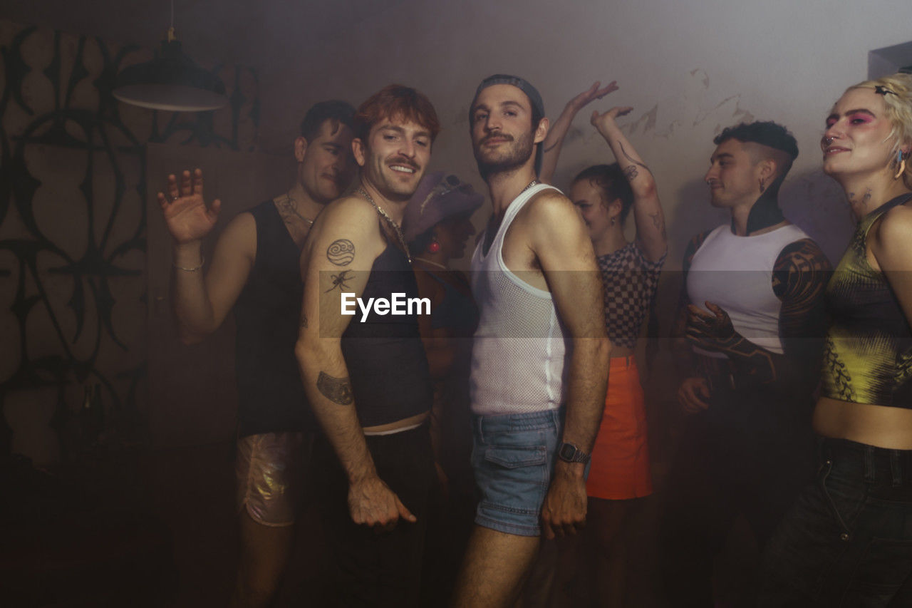 Smiling portrait of gay men clubbing with non-binary friends at nightclub