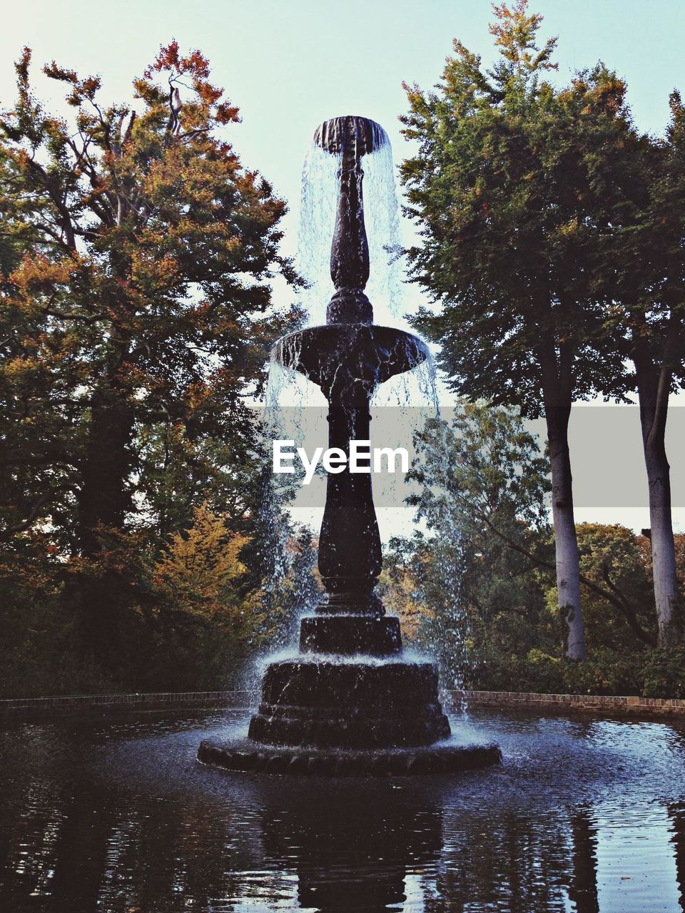 Low angle view of fountain with trees in background