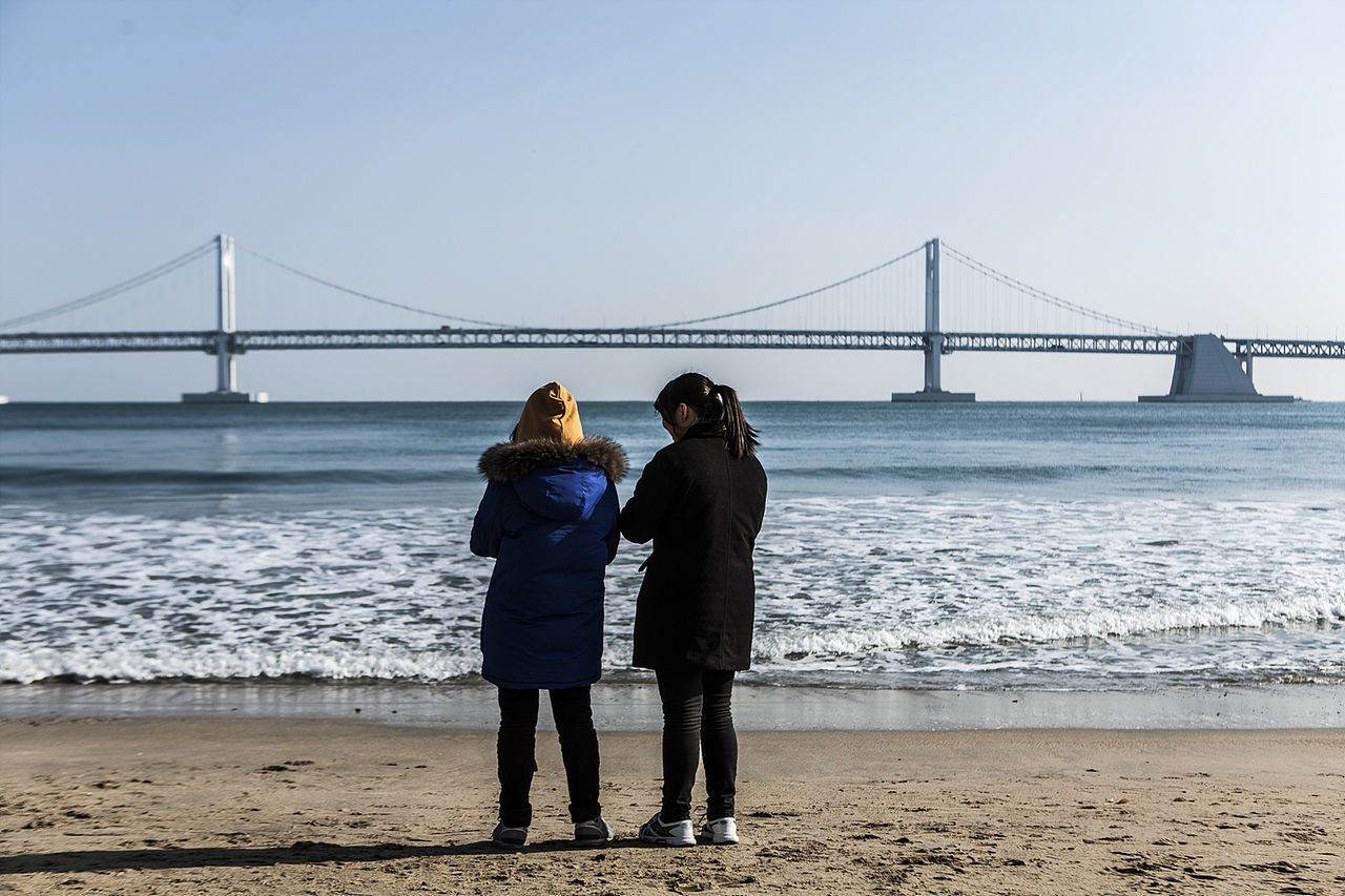 PEOPLE WALKING ON BRIDGE OVER SEA