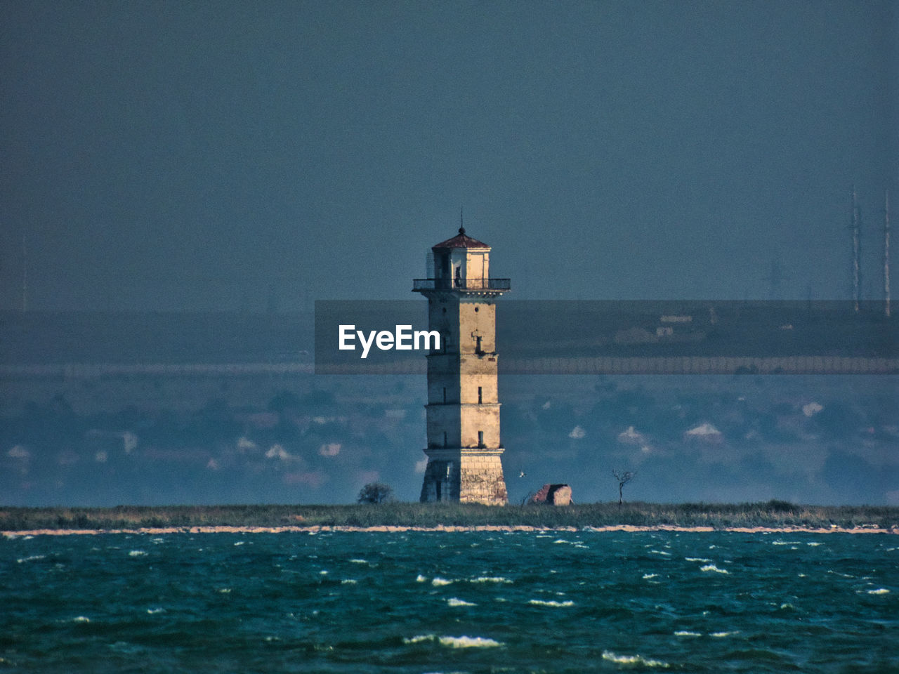 Lighthouse by sea against sky