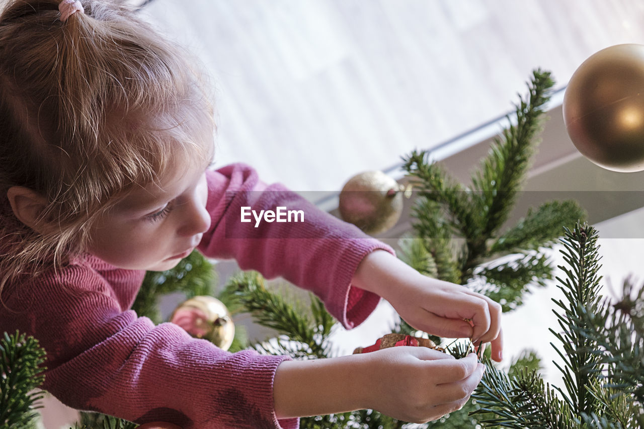 side view of girl playing with christmas tree at home