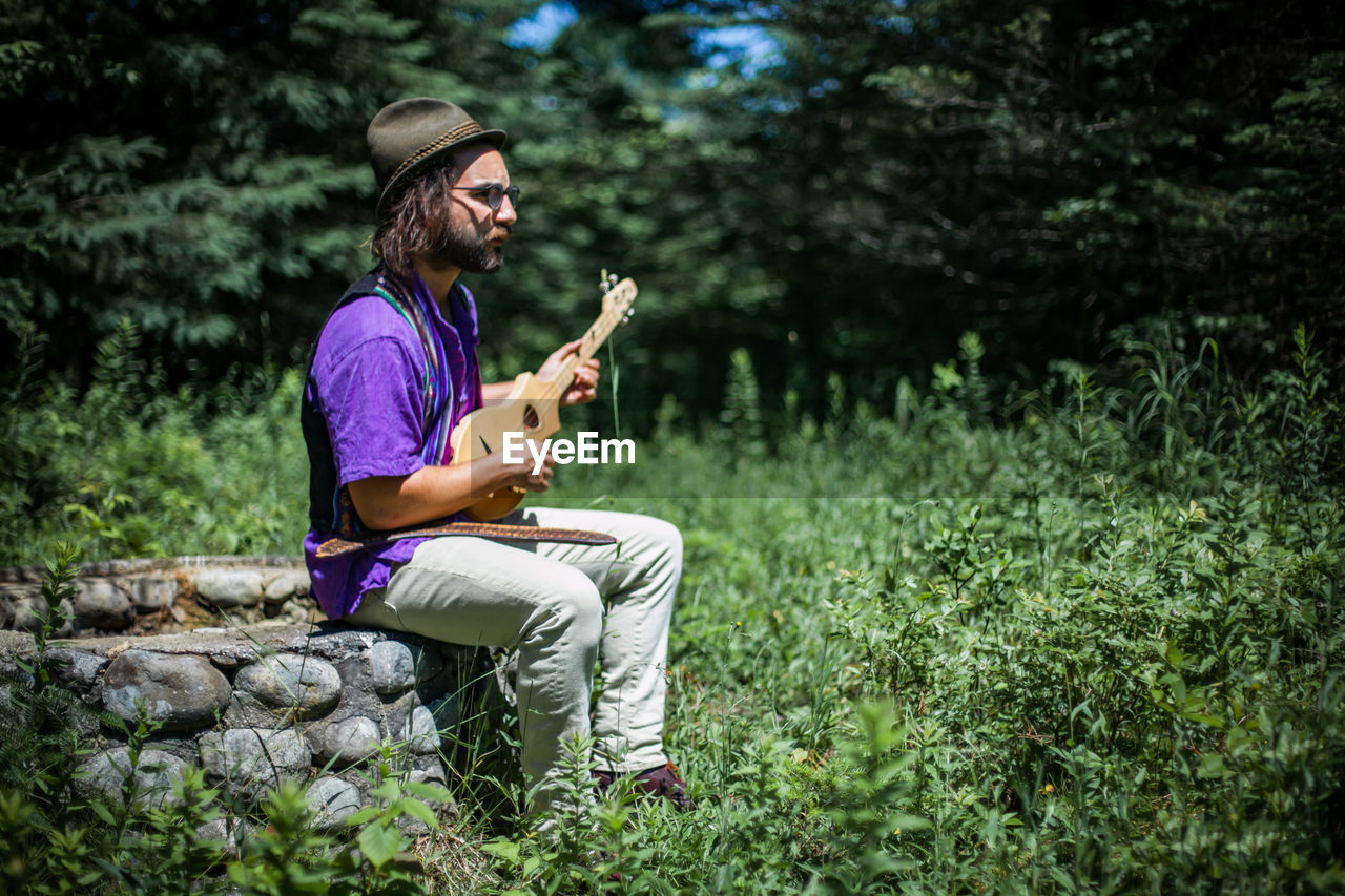 Man playing guitar while sitting outdoors