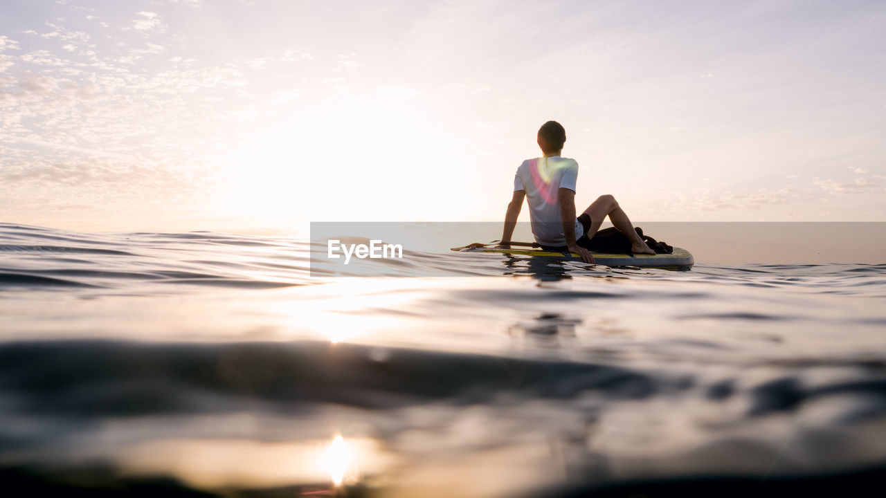 Concept: tranquility and relaxation. man sitting on paddle surf