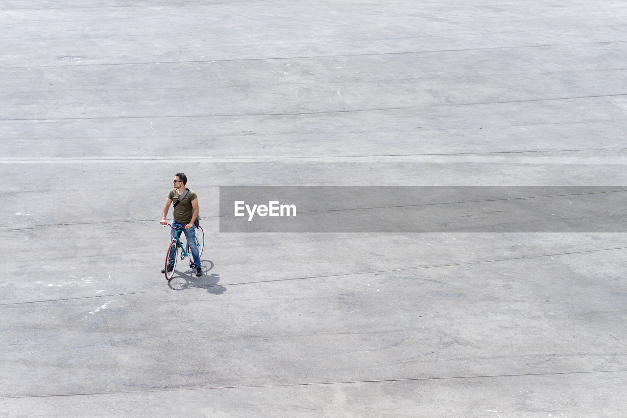 High angle view of mid adult man riding bicycle on street