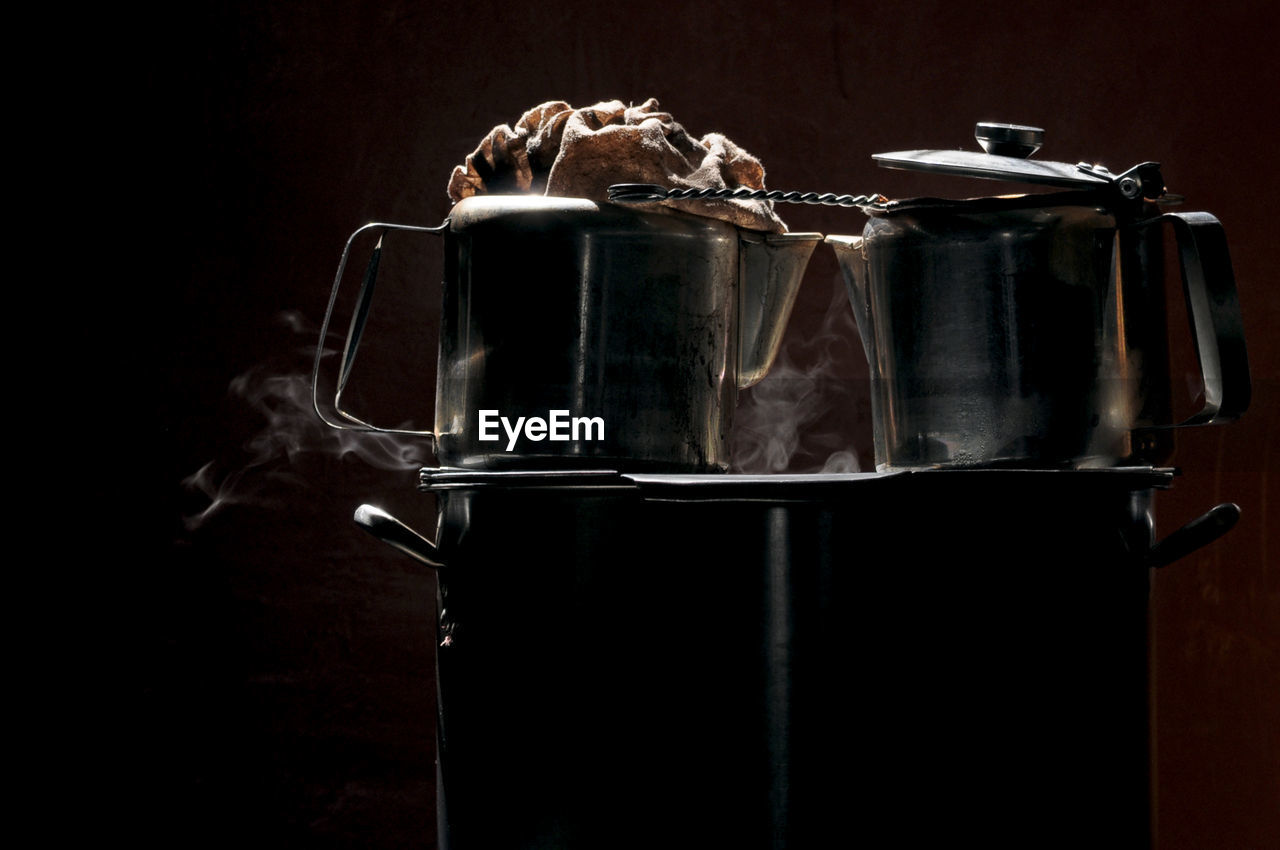 Low key photo of  coffee and teapots on a large pot to boiling water