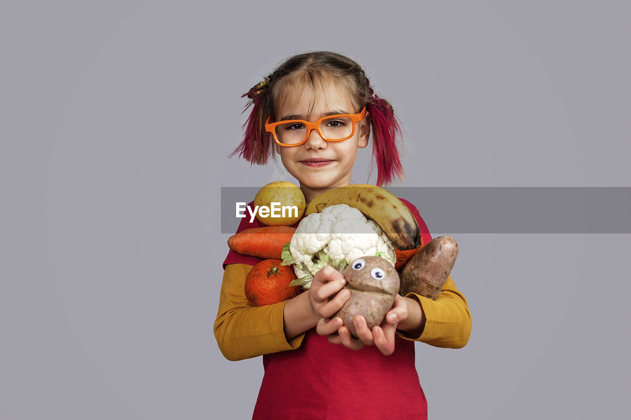 PORTRAIT OF SMILING GIRL HOLDING CAMERA