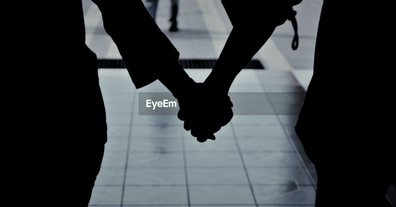 Low section of silhouette people standing on tiled floor