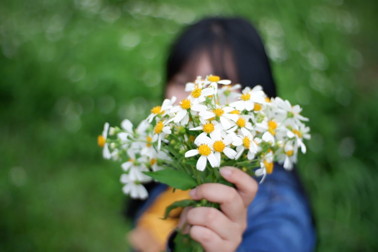 Woman holding flowers in front of face