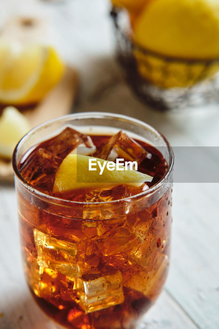 Very cold cola on a white background with ice and lemon