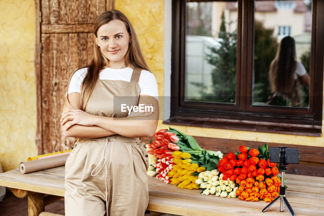 Portrait of a young female florist standing next to a table with tulips on it. women's day 