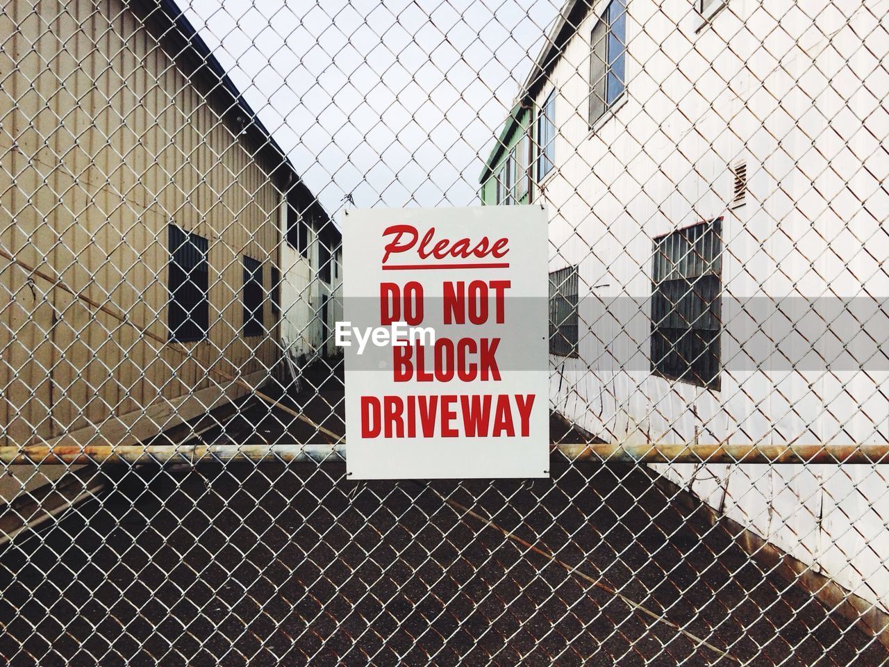 Sign on chainlink fence against buildings