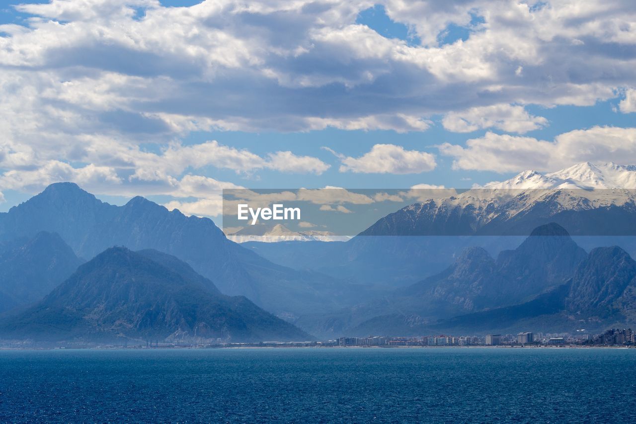 SCENIC VIEW OF SEA AGAINST MOUNTAINS