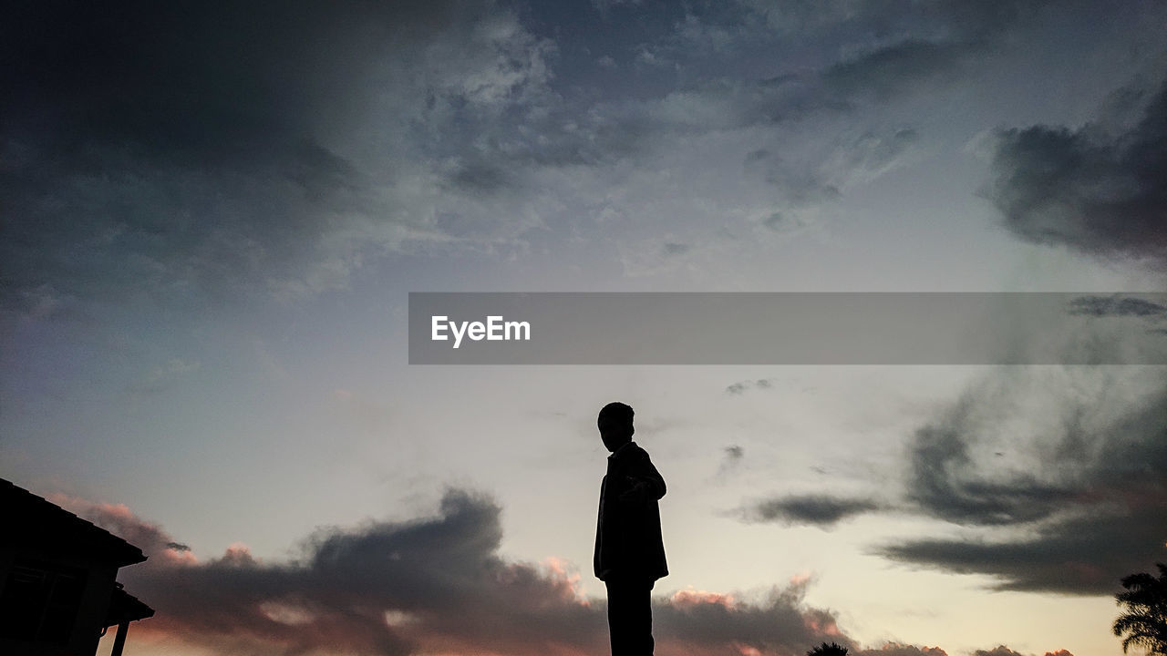 Low angle view of silhouette man standing against sky during sunset