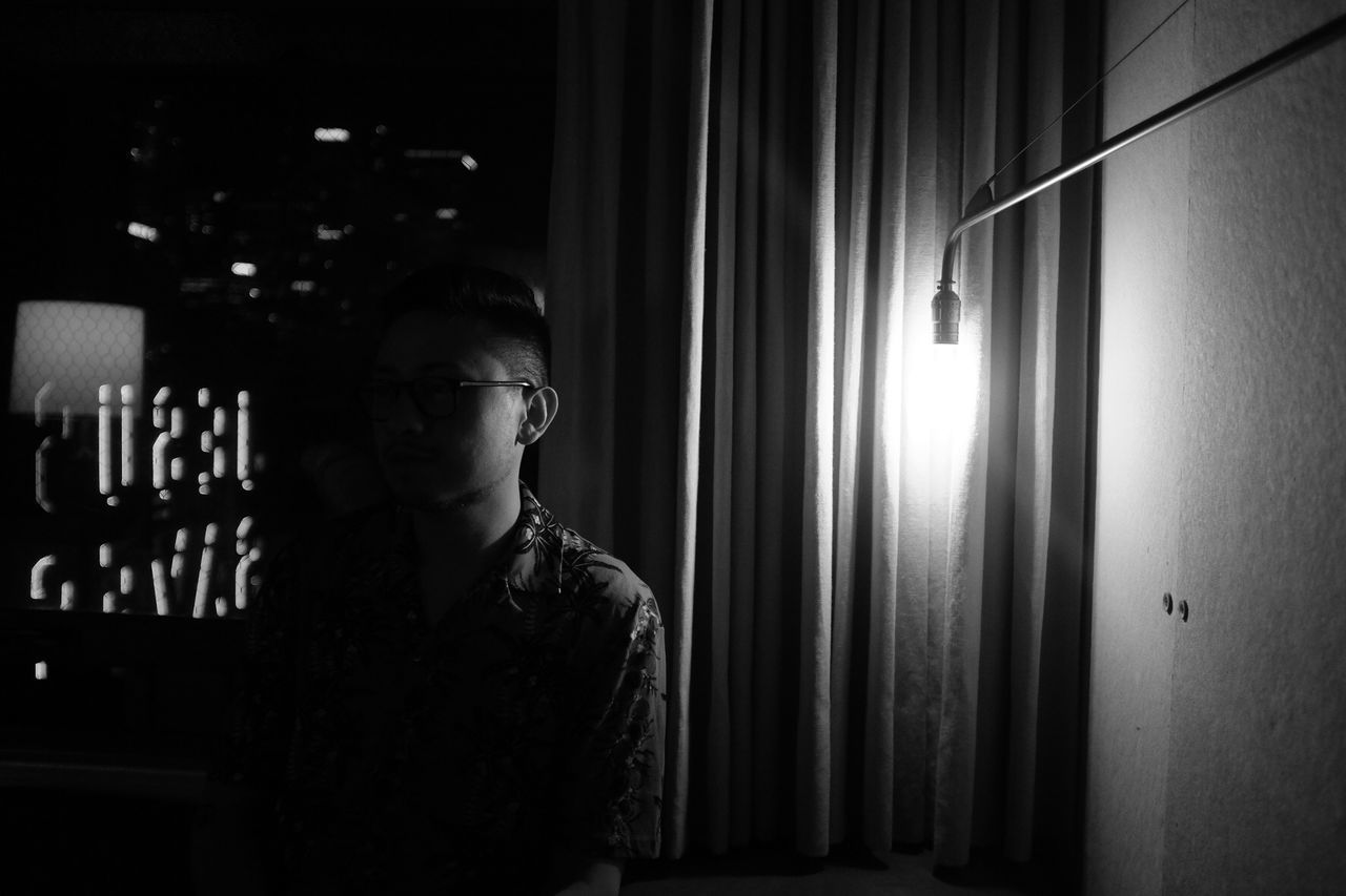 PORTRAIT OF YOUNG MAN LOOKING AWAY AT NIGHT