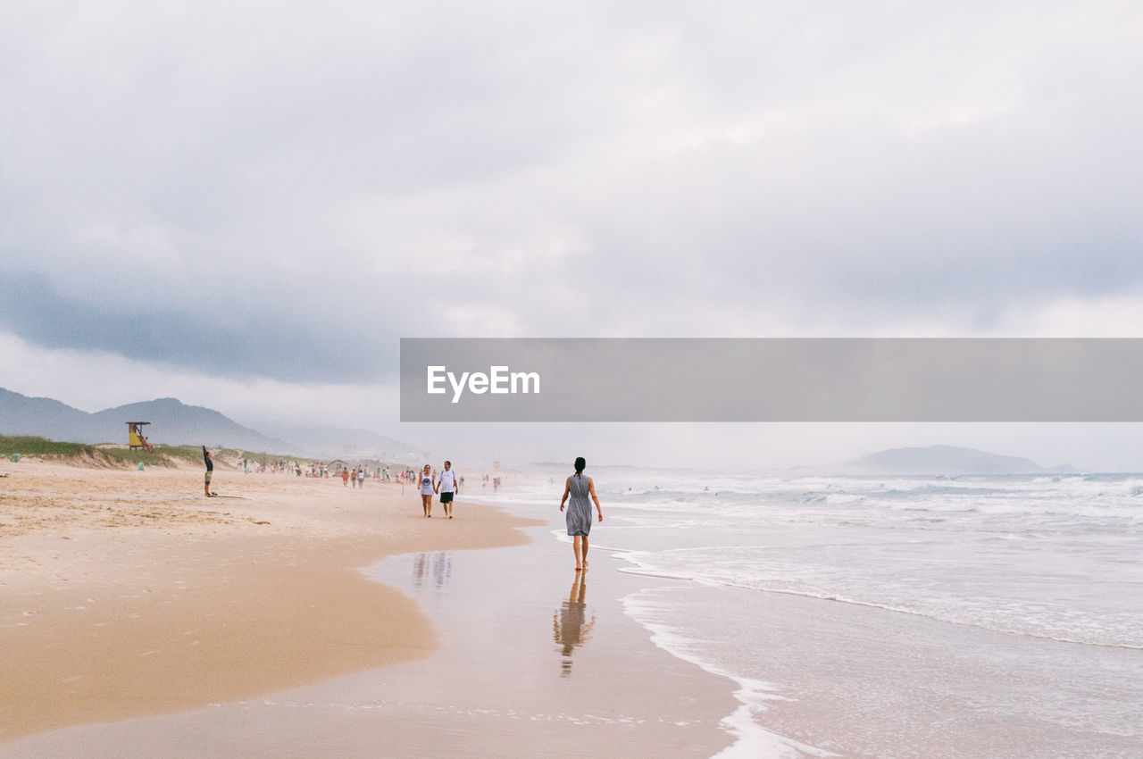 People walking on beach against sky