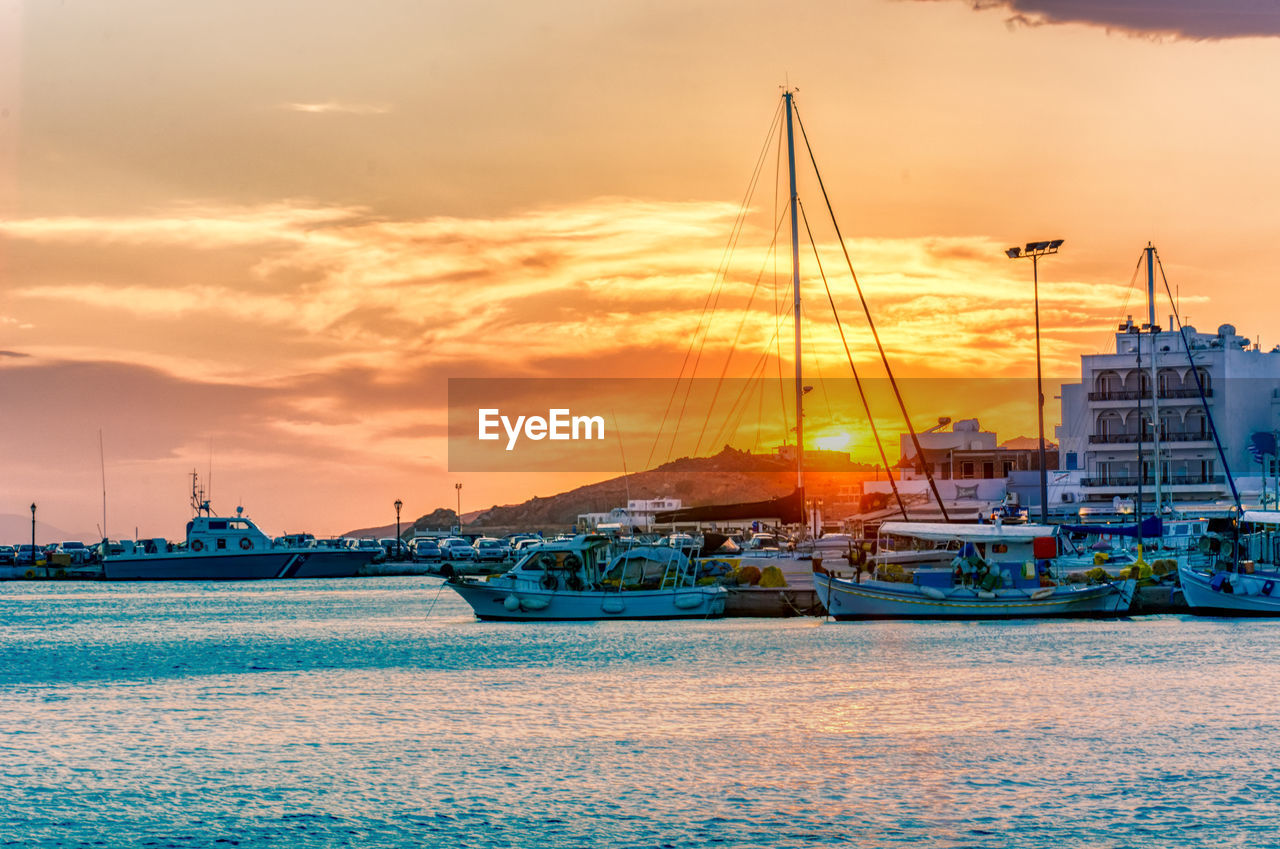 SAILBOATS MOORED IN HARBOR AT SUNSET