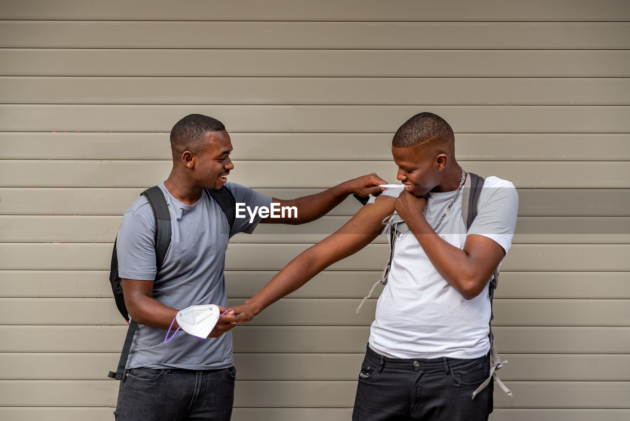 Afro men friends vaccinated showing his arm