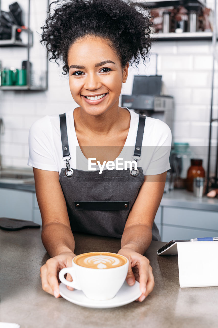 portrait of smiling young woman sitting on table in restaurant