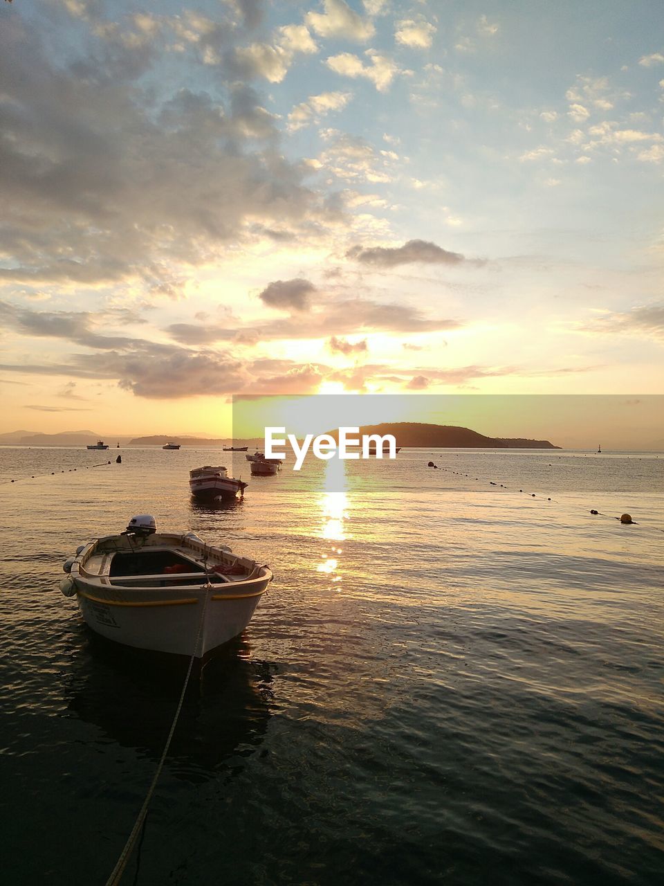 Boats moored on sea against sky during sunset