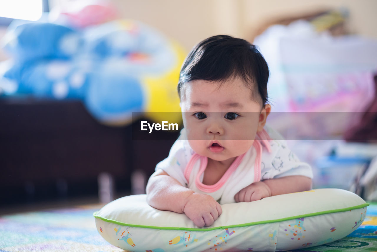 Cute baby girl lying on pillow at home