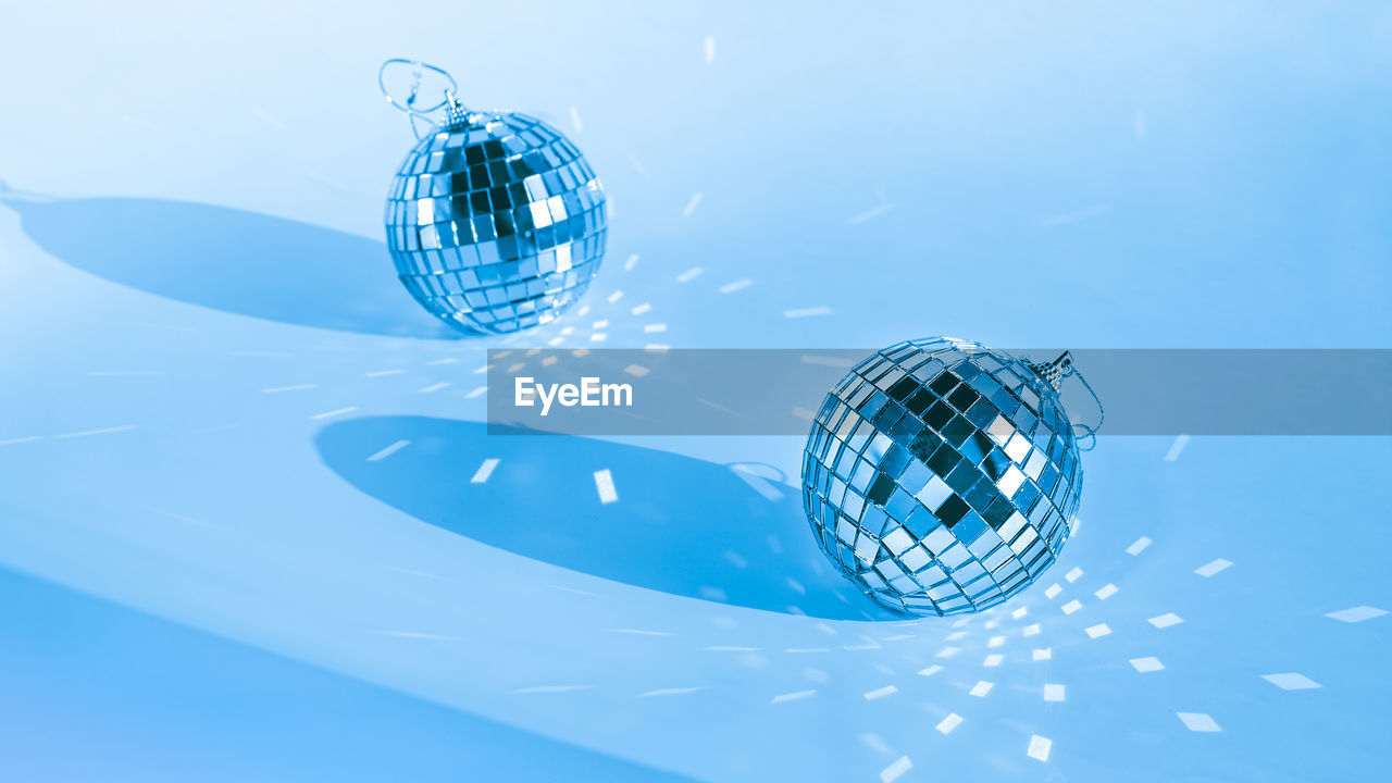 Two disco balls on blue background with shadow and reflections