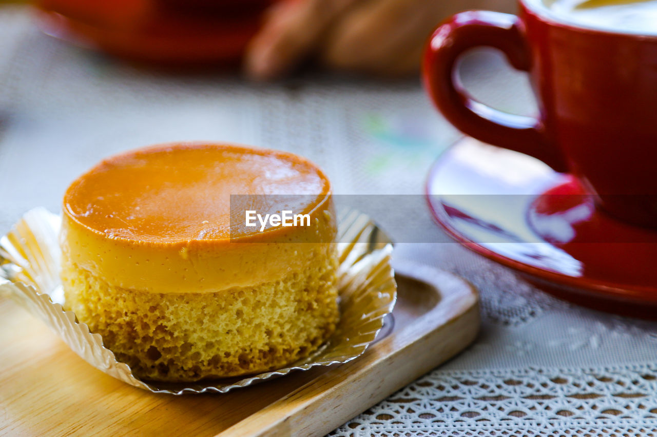 Close-up of coffee cup and  custard cake on table