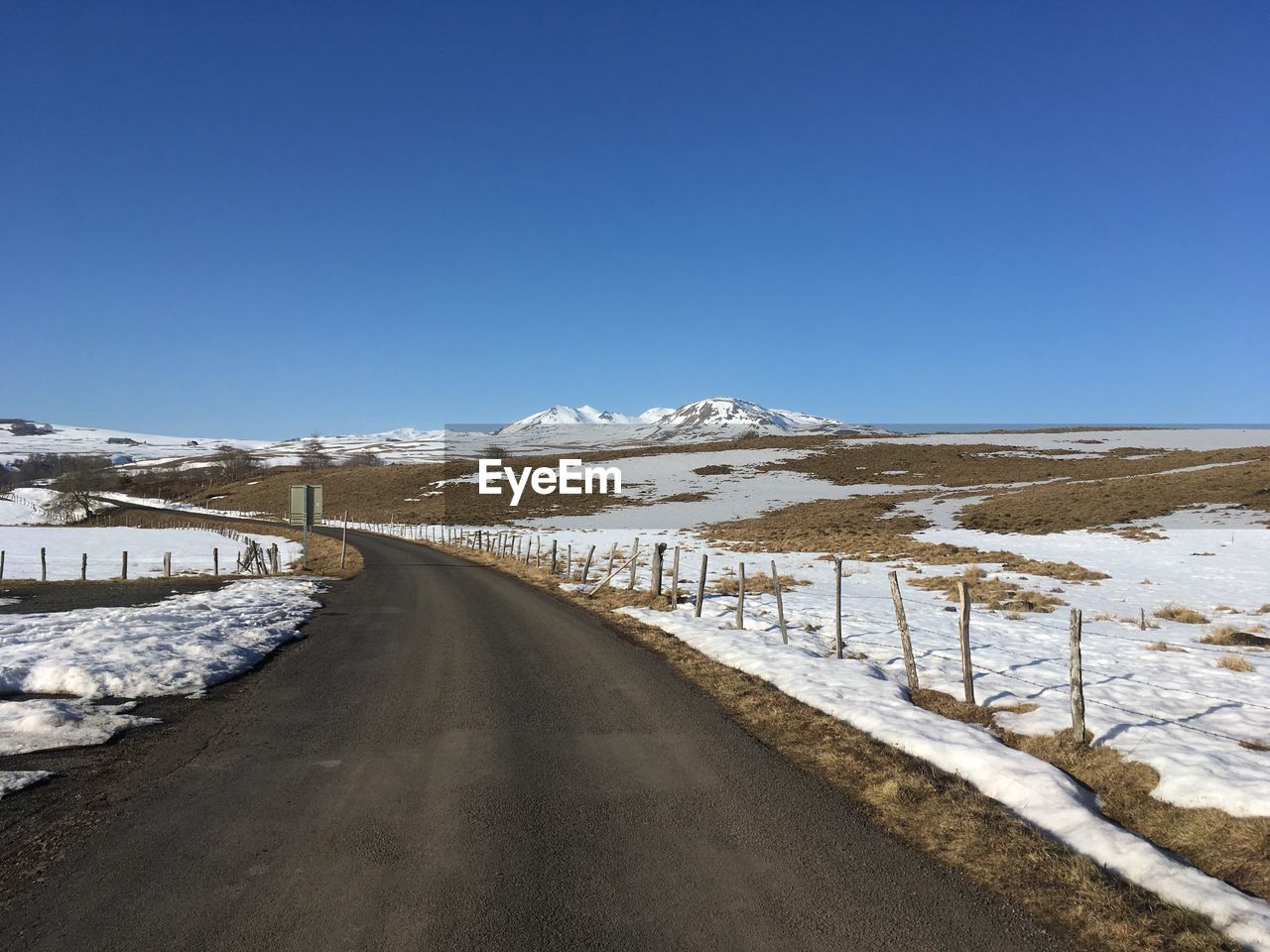 ROAD BY SNOWCAPPED MOUNTAINS AGAINST CLEAR BLUE SKY