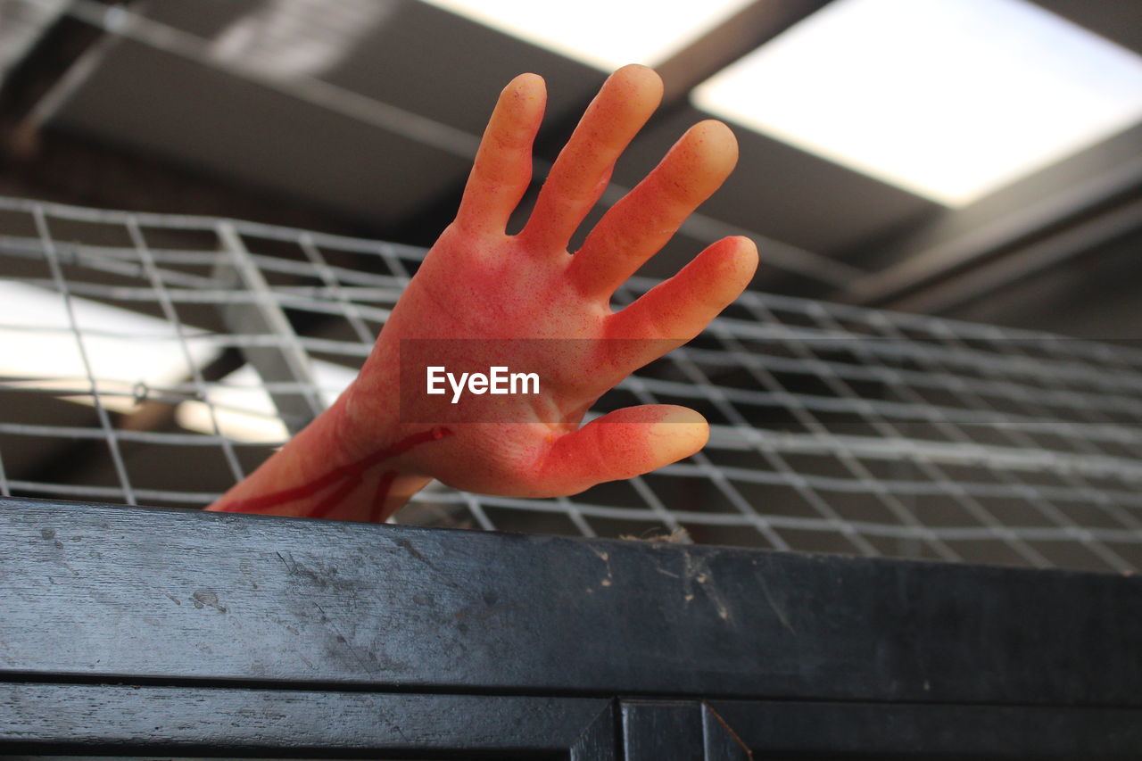 Cropped hand with blood on metal grate