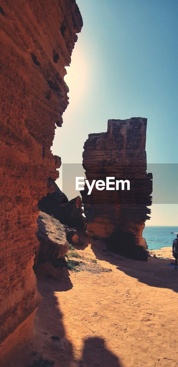 Rock formation on beach against sky