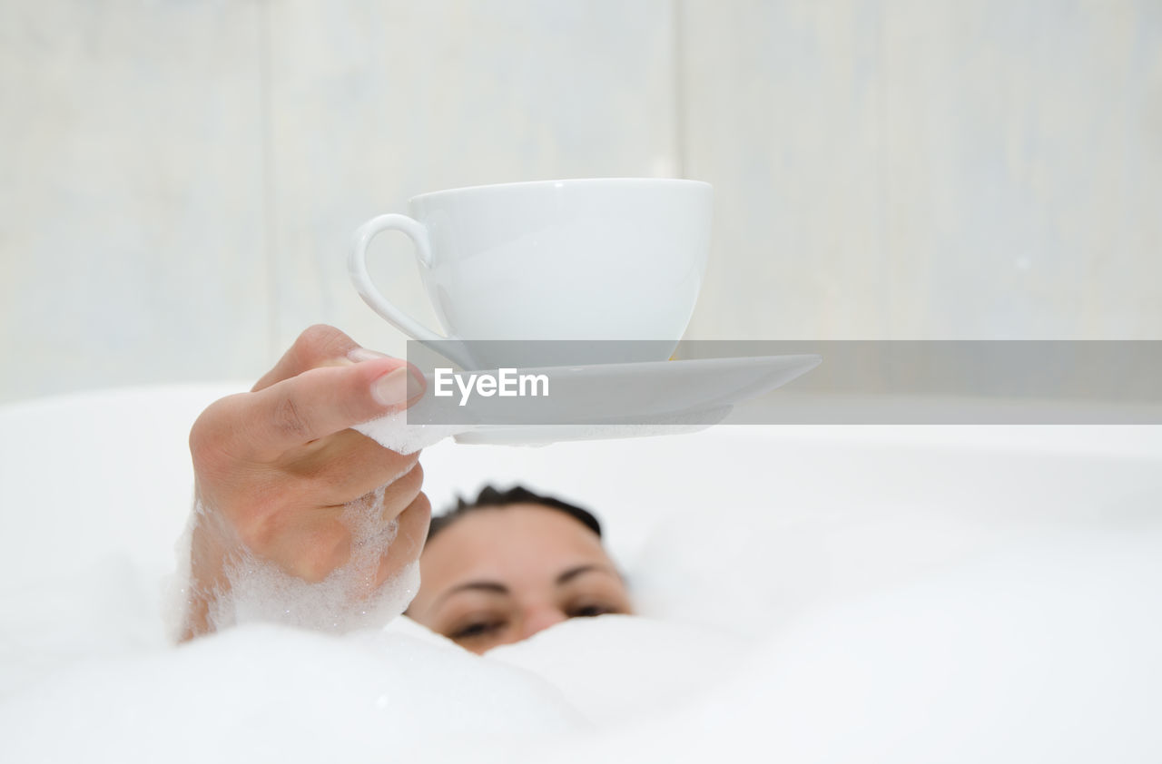 Woman holding cup in bathtub